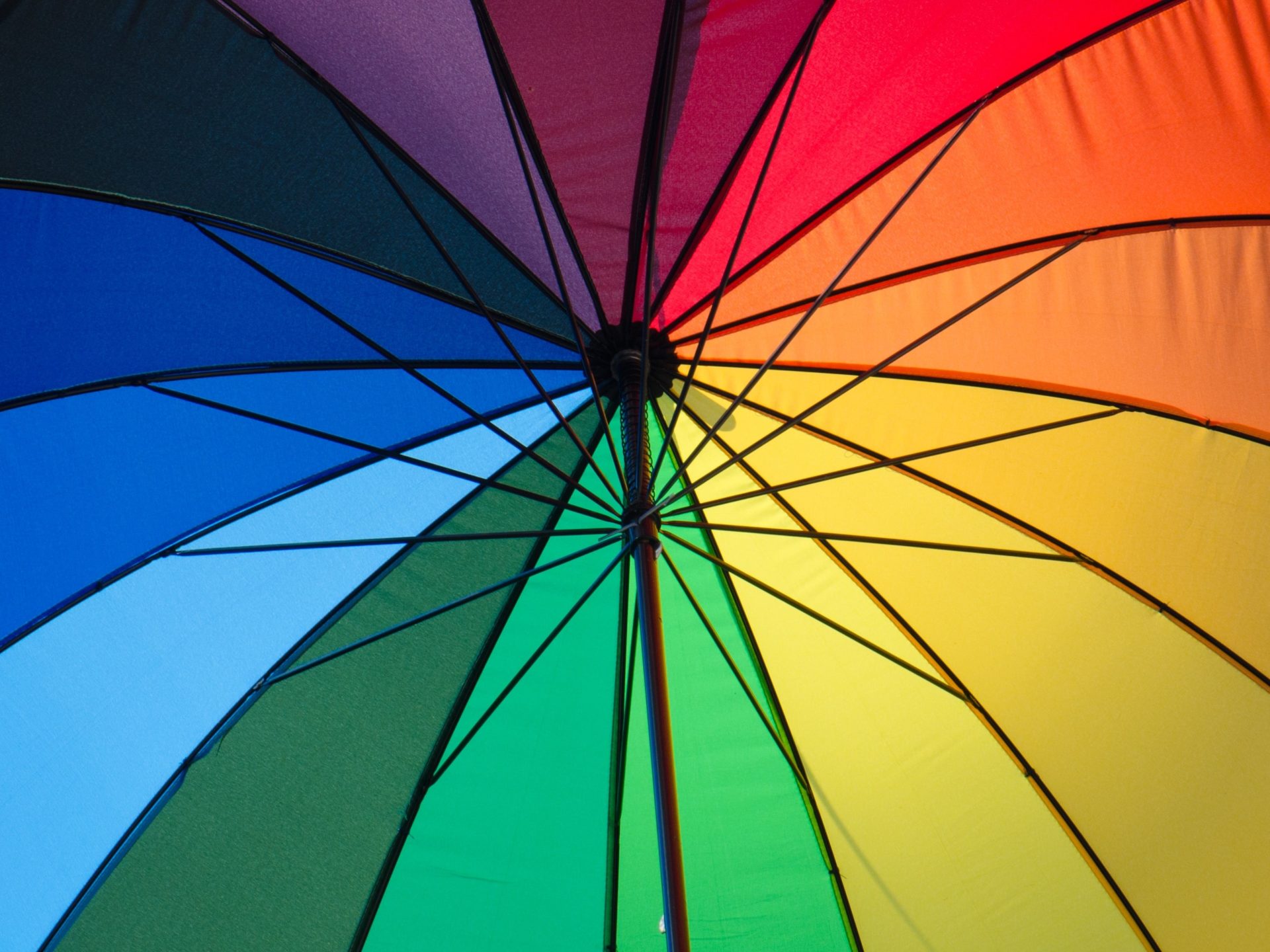 An underneath view of a rainbow coloured umbrella