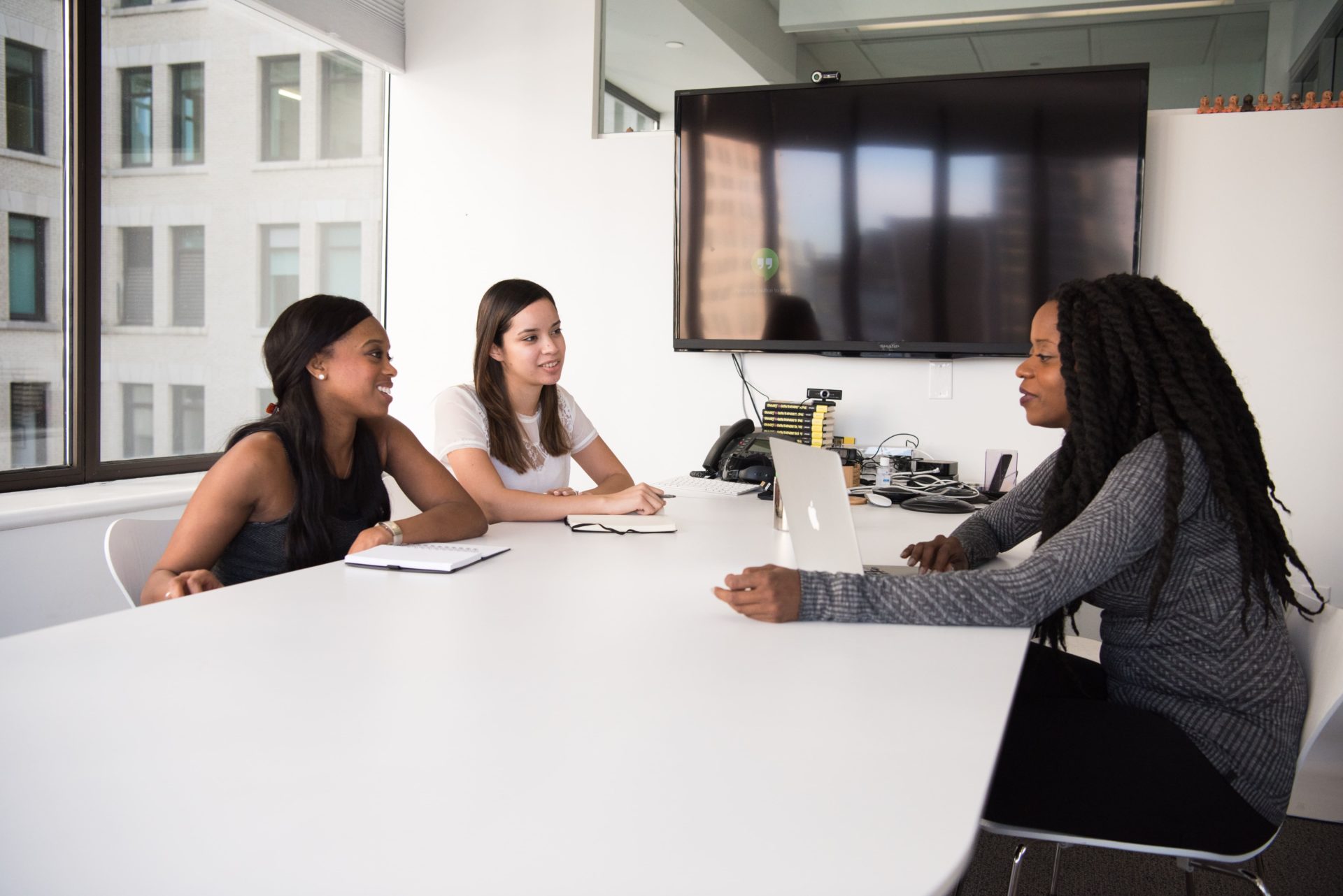 A group of three women discussing across a desk